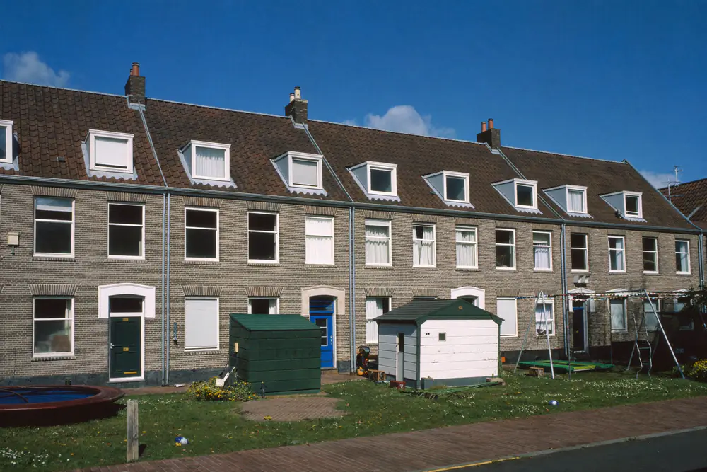 Rij bakstenen woningen met dakkapellen in verschillende breedtes op het dak en kleine voortuinen