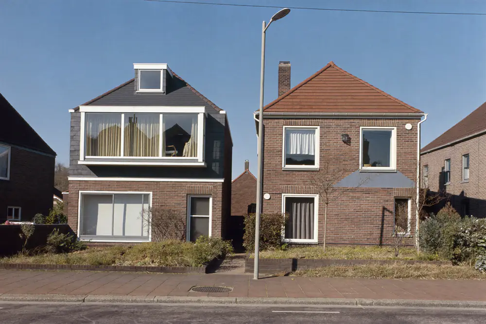 Twee aaneengebouwde woningen onder een kap, waarvan een helft een grote dakkapel heeft